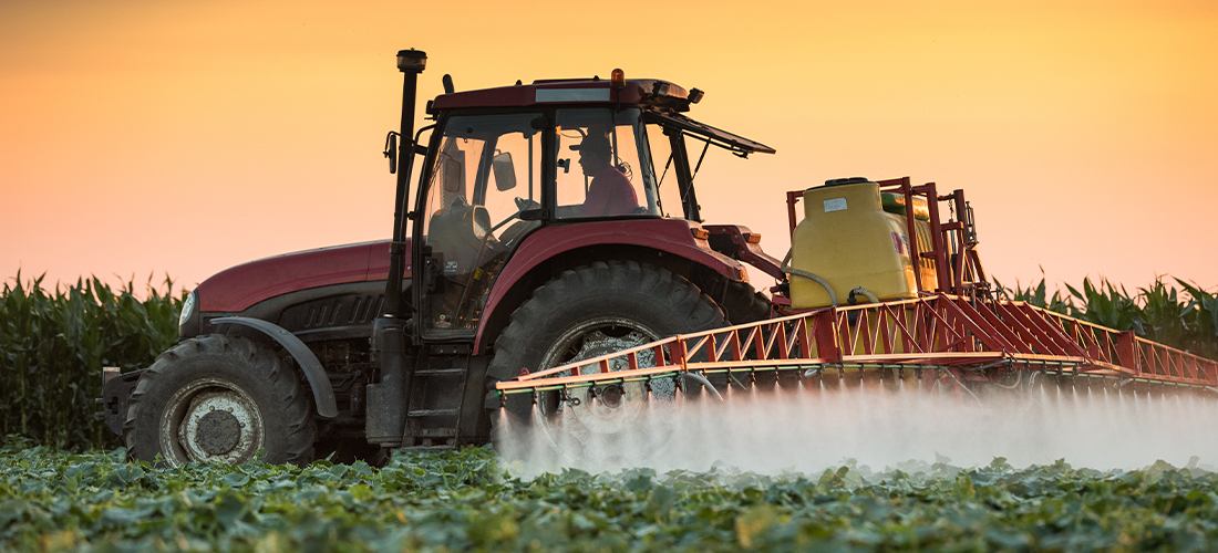 Pesticidas de pulverização de trator em campo vegetal com pulverizador na primavera